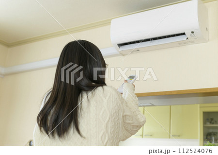 エアコンを操作する寒がっている女性 エアコンを操作する寒がっている女性 112524076