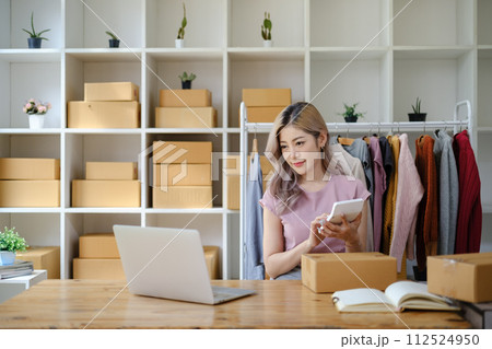 Online shopping concept, Female entrepreneur calculate the order and writes address on parcel boxes. 112524950