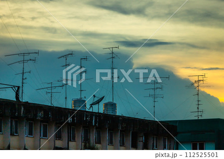 Old style Television (TV) Antenna and satellite on the roof with the house or building in provincial area in orange Twilight dramatic sunset sky with cloud in Thailand,Analog TV receiver panels Old style Television (TV) Antenna and satellite on the roof with the house or building in provincial area in orange Twilight dramatic sunset sky with cloud in Thailand,Analog TV receiver panels 112525501
