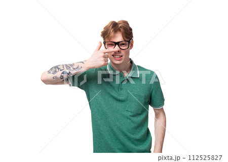 portrait of a young man with red hair dressed in a green T-shirt grimacing 112525827