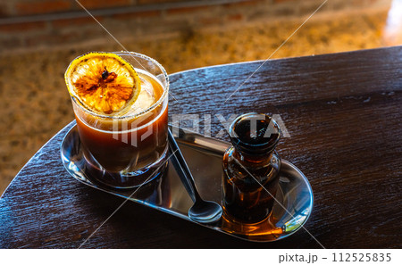 Iced Black americano Orange Coffee topping with mint leaves and sliced in a glass on wooden background in coffee shop cafe. 112525835