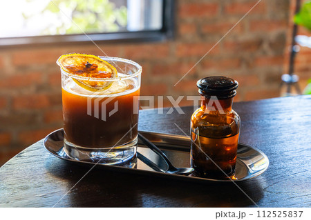Iced Black americano Orange Coffee topping with mint leaves and sliced in a glass on wooden background in coffee shop cafe. Iced Black americano Orange Coffee topping with mint leaves and sliced in a glass on wooden background in coffee shop cafe. 112525837