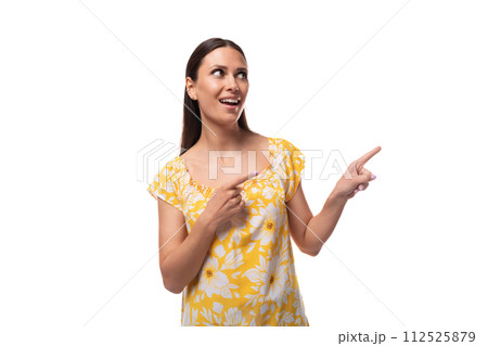 brunette young woman dressed in a summer yellow outfit points her finger to the side brunette young woman dressed in a summer yellow outfit points her finger to the side 112525879