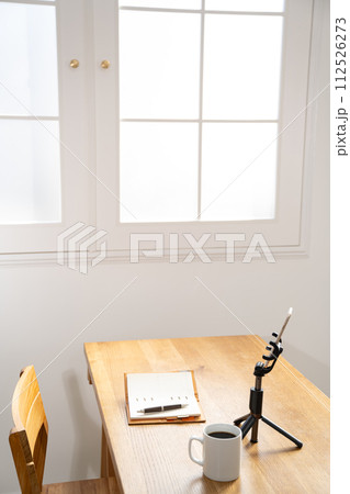 机の上に置かれたシステム手帳とスマホ 112526273