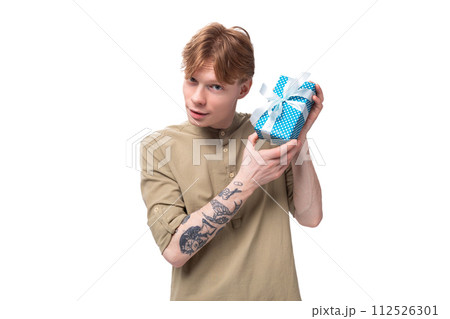 a young red-haired guy in glasses and a brown shirt decides who to give a gift box with a surprise a young red-haired guy in glasses and a brown shirt decides who to give a gift box with a surprise 112526301