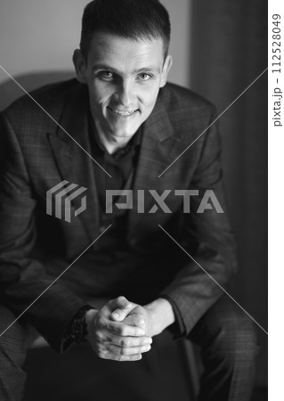 Portrait of a young man in a plaid suit on a chair. Business portrait. Portrait of a young man in a plaid suit on a chair. Business portrait. 112528049