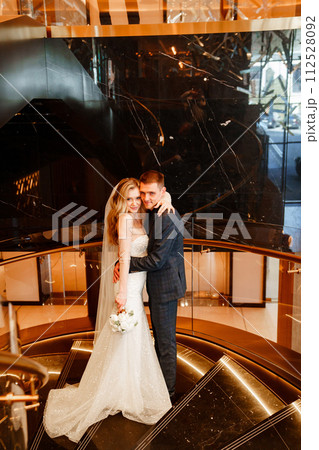 Bride and groom embracing on a golden spiral staircase.  112528092