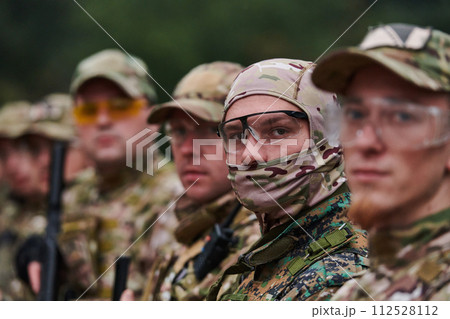 Soldier fighters standing together with guns. Group portrait of US army elite members, private military company servicemen, anti terrorist squad Soldier fighters standing together with guns. Group portrait of US army elite members, private military company servicemen, anti terrorist squad 112528112