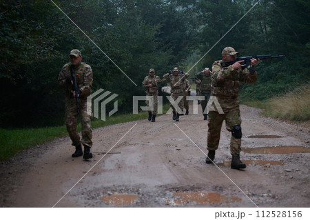 A group of elite soldiers leads captives through a military camp, showcasing a tense atmosphere of detention and security operations 112528156