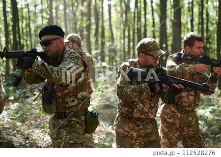A specialized military antiterrorist unit conducts a covert operation in dense, hazardous woodland, demonstrating precision, discipline, and strategic readiness 112528276