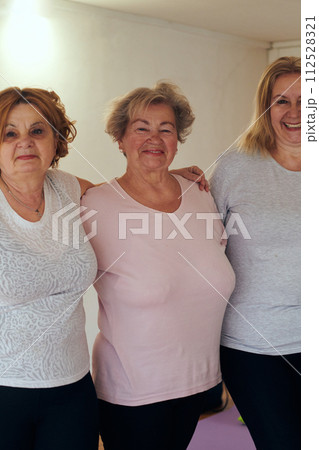 A vibrant community of senior women, guided by their instructor, embraces the enriching journey of yoga, fostering unity, well-being, and a shared commitment to active aging A vibrant community of senior women, guided by their instructor, embraces the enriching journey of yoga, fostering unity, well-being, and a shared commitment to active aging 112528321
