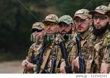 Soldier fighters standing together with guns. Group portrait of US army elite members, private military company servicemen, anti terrorist squad Soldier fighters standing together with guns. Group portrait of US army elite members, private military company servicemen, anti terrorist squad 112528322