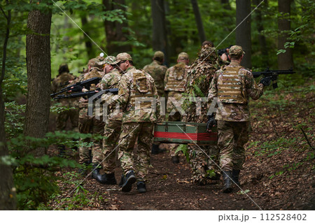 Elite military unit, cloaked in camouflage, transports a crate of ammunition through the dense forest, epitomizing strategic readiness and precision in their covert mission Elite military unit, cloaked in camouflage, transports a crate of ammunition through the dense forest, epitomizing strategic readiness and precision in their covert mission 112528402