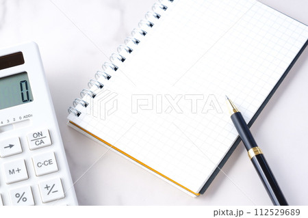 電卓とペン、メモ帳でデスクワークをしているイメージ 電卓とペン、メモ帳でデスクワークをしているイメージ 112529689