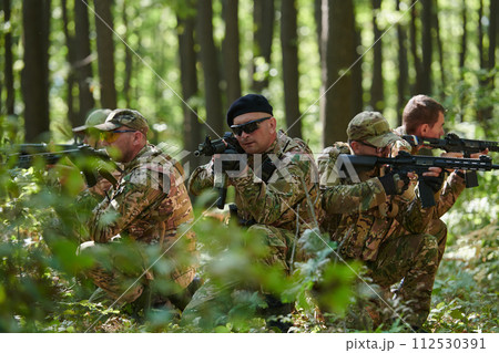 A specialized military antiterrorist unit conducts a covert operation in dense, hazardous woodland, demonstrating precision, discipline, and strategic readiness 112530391