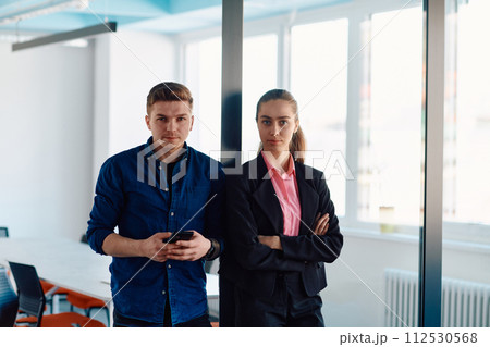 The director of an IT company poses with her colleague in a modern startup office setting The director of an IT company poses with her colleague in a modern startup office setting 112530568