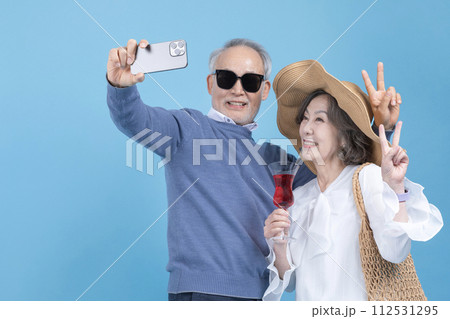 Senior who looks at smartphone and drinks wine Senior who looks at smartphone and drinks wine 112531295