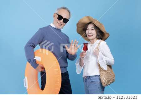 A senior greets a middle aged man with a tube and a middle aged woman with a wide brim hat 112531323