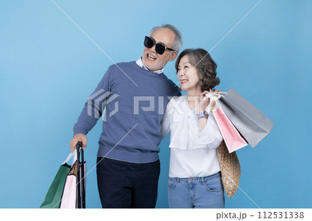 Senior carrying a suitcase and a shopping bag 112531338