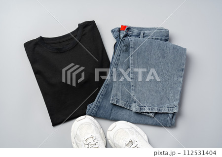 T-shirt, jeans and white sneakers on gray background top view 112531404