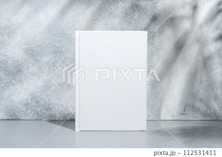White blank book with hard cover on gray background with shadows White blank book with hard cover on gray background with shadows 112531411