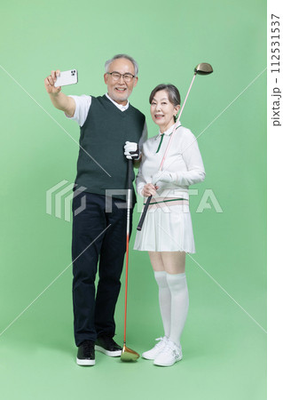 A senior who holds a golf club and takes pictures with a smartphone A senior who holds a golf club and takes pictures with a smartphone 112531537