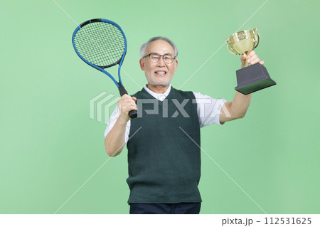 A senior man with a tennis racket and a trophy A senior man with a tennis racket and a trophy 112531625
