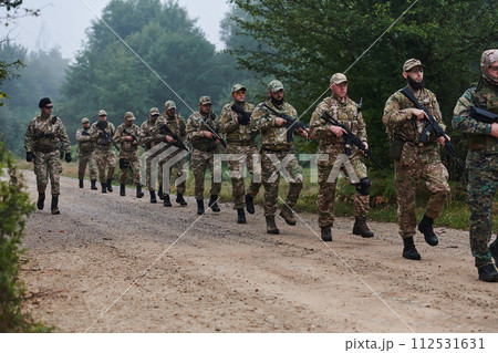 An elite military unit, led by a major, confidently parades through dense forest, showcasing precision, discipline, and readiness for high-risk operations An elite military unit, led by a major, confidently parades through dense forest, showcasing precision, discipline, and readiness for high-risk operations 112531631