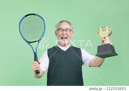 A senior man with a tennis racket and a trophy A senior man with a tennis racket and a trophy 112531653