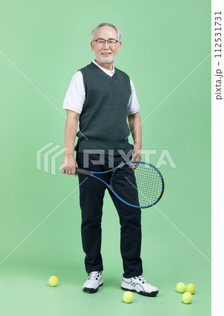 A senior male holding a tennis racket and a tennis ball A senior male holding a tennis racket and a tennis ball 112531731