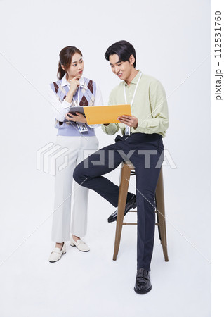 A man and a woman talking to a tablet while filing 112531760