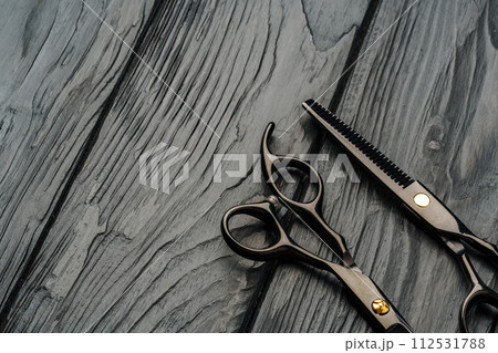 Hairdressing scissors on black wooden background close up 112531788