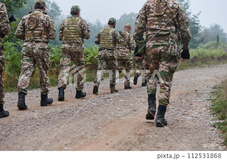 An elite military unit, led by a major, confidently parades through dense forest, showcasing precision, discipline, and readiness for high-risk operations 112531868