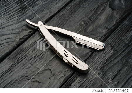 Sharp shaving razor on black wooden background Sharp shaving razor on black wooden background 112531967