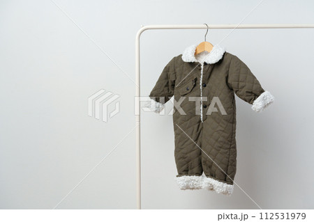 Baby gray quilted winter overalls on hanger against white wall Baby gray quilted winter overalls on hanger against white wall 112531979
