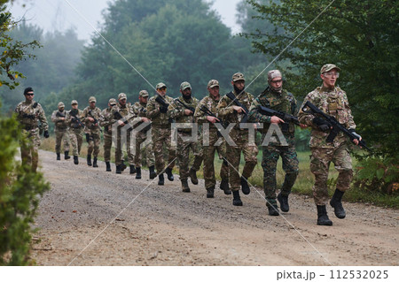 An elite military unit, led by a major, confidently parades through dense forest, showcasing precision, discipline, and readiness for high-risk operations An elite military unit, led by a major, confidently parades through dense forest, showcasing precision, discipline, and readiness for high-risk operations 112532025