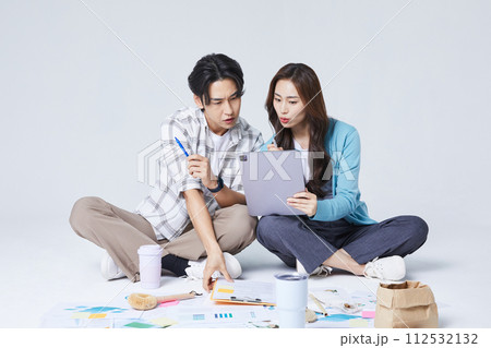 A man and a woman sitting on two legs and holding a tablet and talking A man and a woman sitting on two legs and holding a tablet and talking 112532132