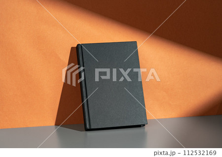 Black notepad mock up against terracotta wall 112532169