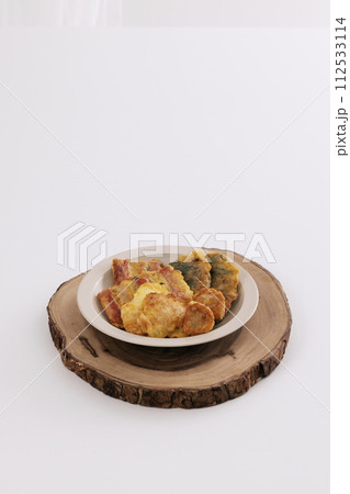 There's a bowl of jeon on a wooden chopping board There's a bowl of jeon on a wooden chopping board 112533114