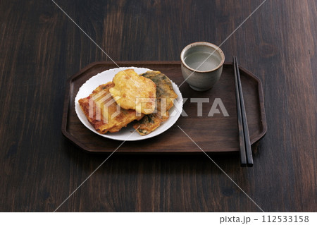 There are group pancakes, chopsticks, and glasses in the background of a wooden table 112533158