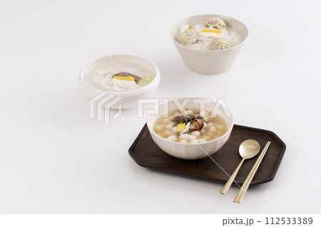 On a white table, three bowls of rice cake soup are placed with kimchi 112533389