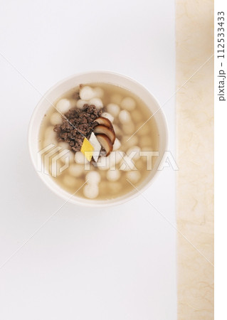 On a white table covered with Korean paper, a white bowl of gourd-shaped rice cake soup was placed 112533433