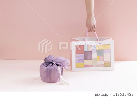 hold a traditional patterned shopping bag next to a gift cloth 112533455