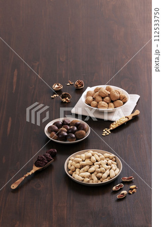 Walnuts, chestnuts, pine nuts, peanuts, and jujube are filled in plates and wooden spoon Walnuts, chestnuts, pine nuts, peanuts, and jujube are filled in plates and wooden spoon 112533750