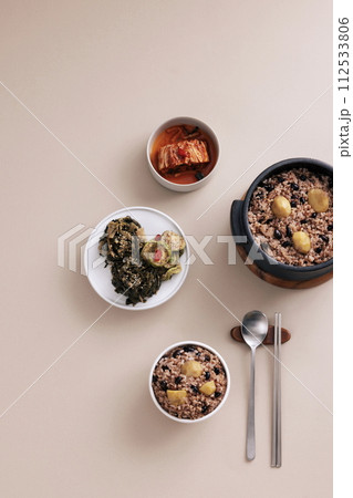 Five grain rice and dried vegetables are served in a bowl and there are spoons Five grain rice and dried vegetables are served in a bowl and there are spoons 112533806