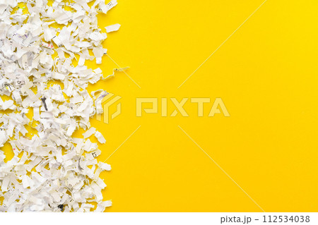 Shredded white paper on light yellow background Shredded white paper on light yellow background 112534038