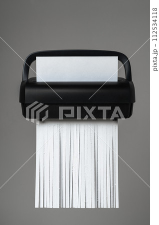 Black paper shredder cutting paper on gray background Black paper shredder cutting paper on gray background 112534118