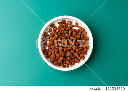 Bowl of dry pet food on green background 112534220