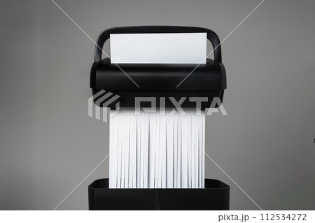 Black paper shredder cutting paper on gray background 112534272