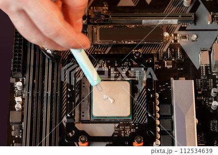 Man applies thermal paste to the CPU 112534639